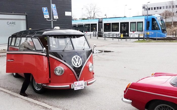 En högerstyrd Volkswagen Lyxbuss Camping från 1955 på väg att starta samtidigt som Lidingöbanan rullar ut från Gåshaga brygga.